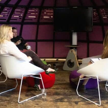 Four People Having a Discussion in a Modern Office Lounge with Unique Curved Architecture and Vibrant Colors