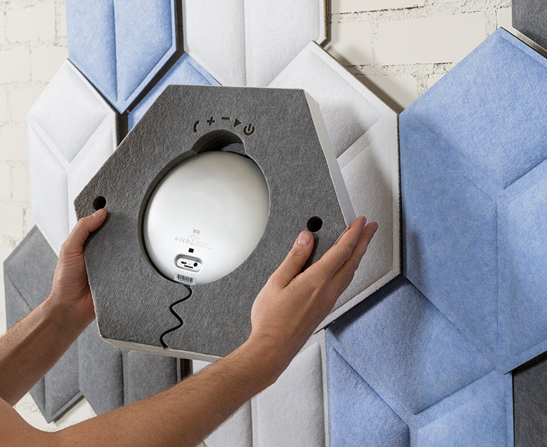 Hands Installing a Hexagonal Acoustic Panel on a Wall