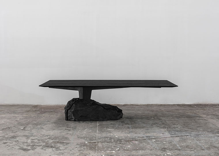 Modern Black Table Featuring a Natural Rock Base in a Minimalistic Setting