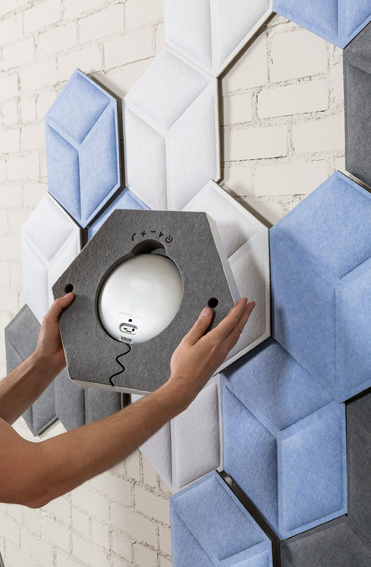 Hands Installing a Hexagonal Sound Panel on a Wall