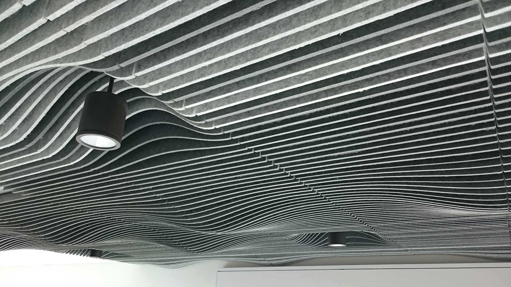 Modern wave-designed ceiling with integrated spotlights, showcasing aesthetic and functional design.