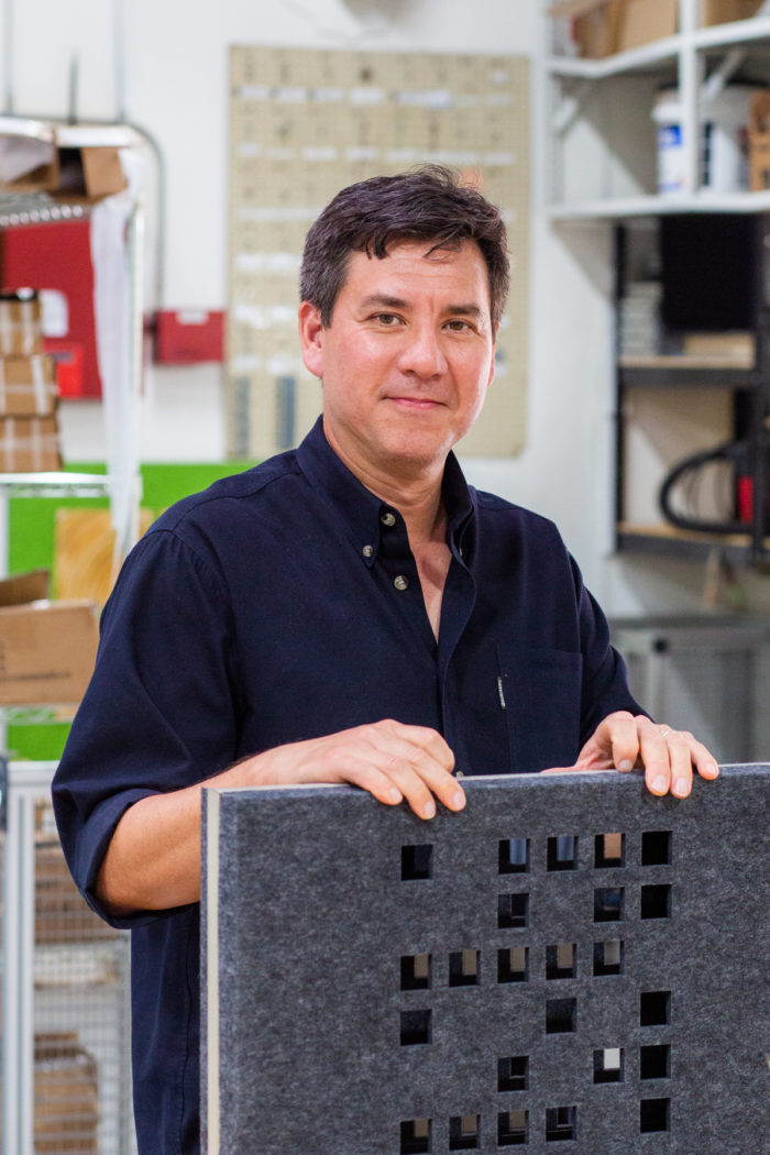 Man Holding a Perforated Panel in a Workshop Environment